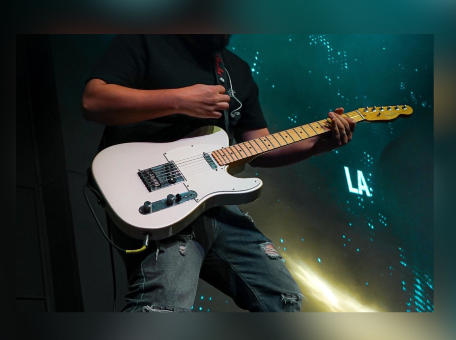 Guitarrista tocando guitarra eléctrica blanca durante una presentación en vivo